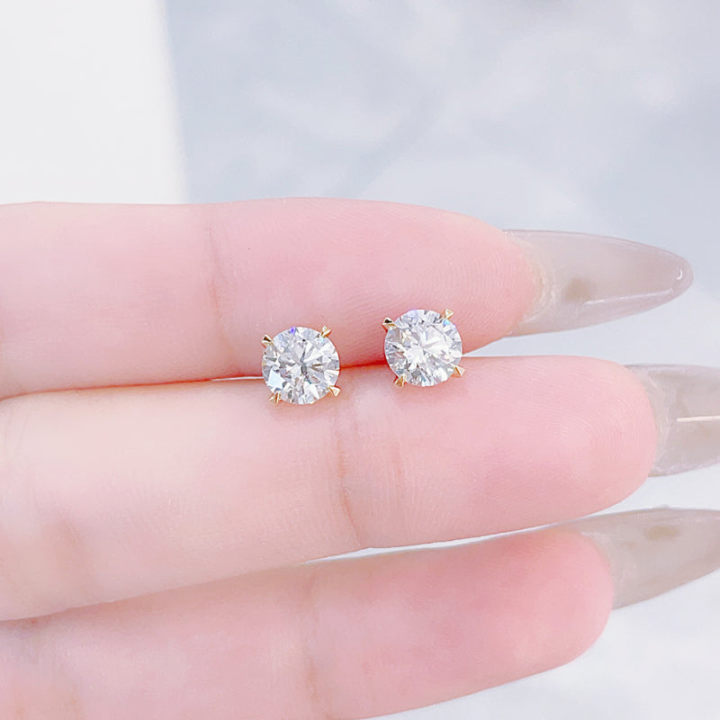 Close-up of Classic Four-Prong round lab-grown diamond stud earrings with yellow gold prongs