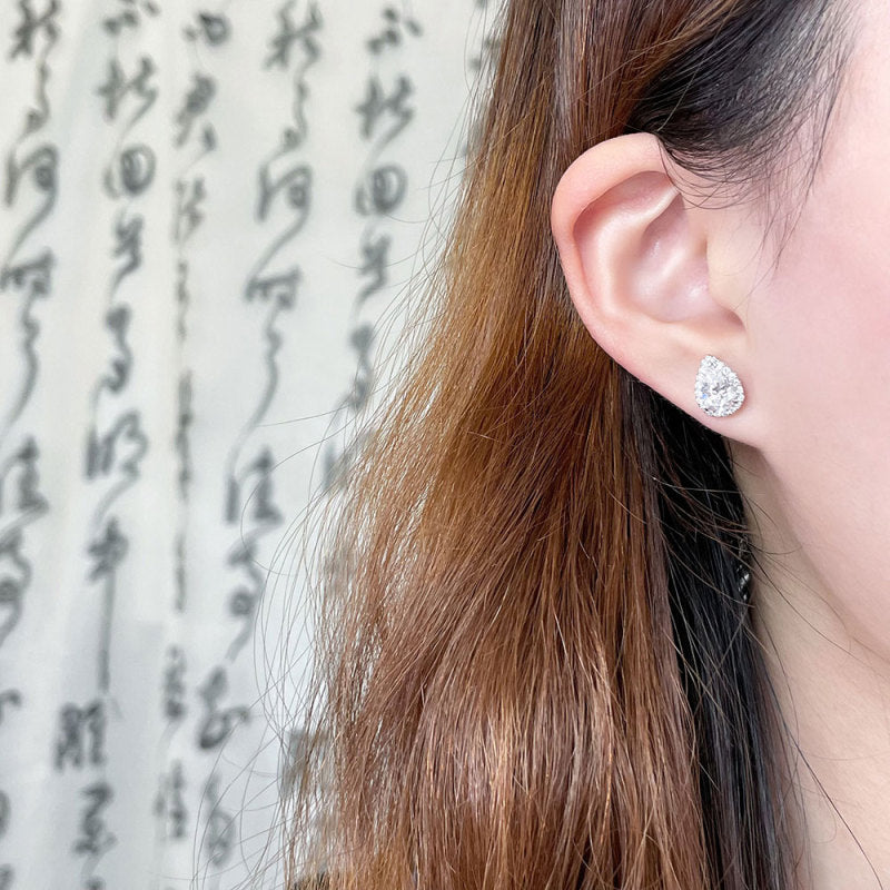 Model wearing Pear Halo lab-grown diamond stud earrings with pear-cut center diamonds and halo settings