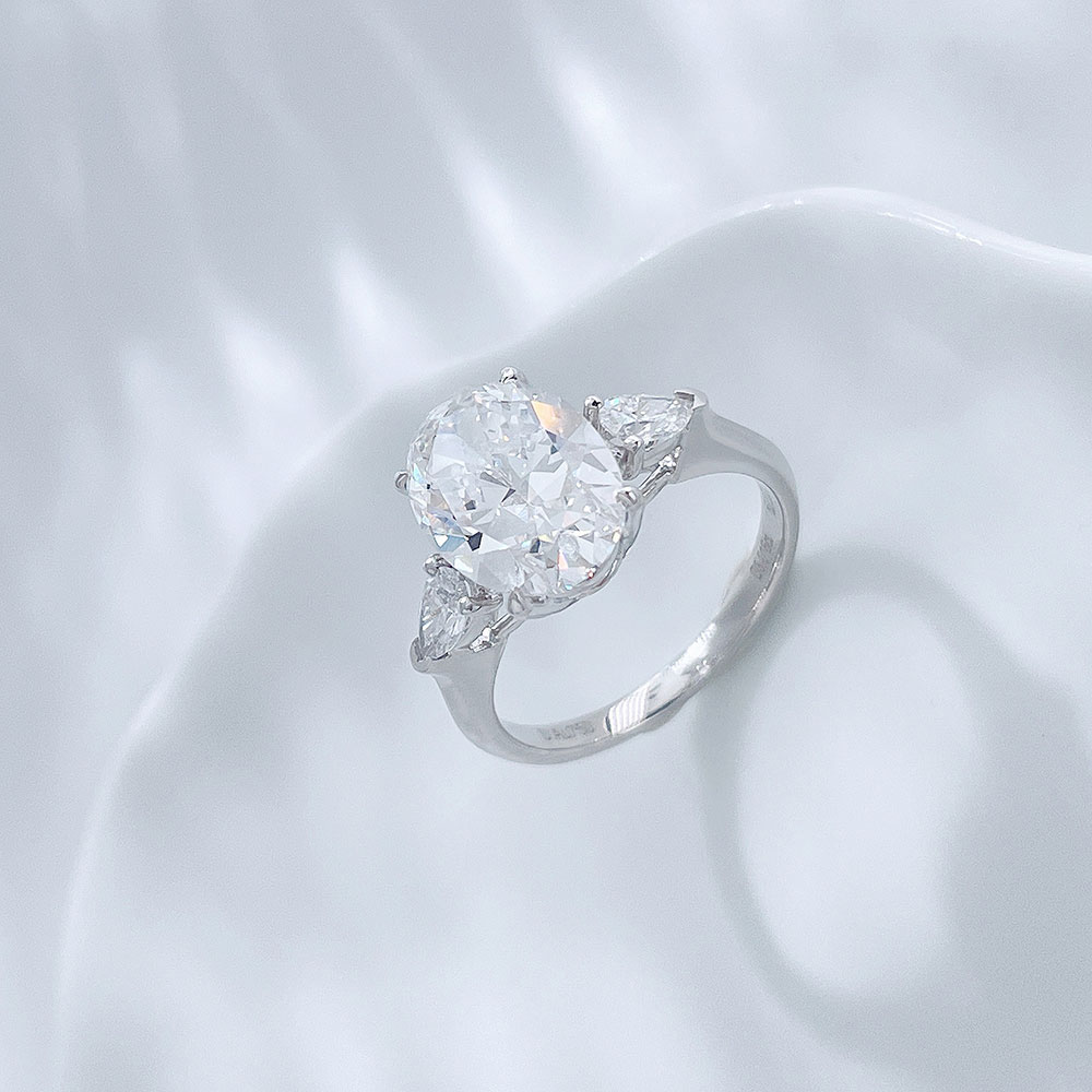 Angled view of the Soft Oval Trio lab-grown diamond engagement ring with an oval center diamond and delicate side stones